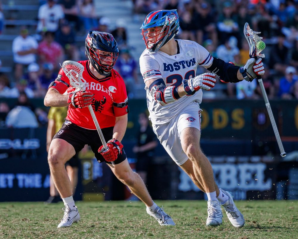 Boston Canon's Lacrosse player cradles the ball past a Caroline Chaos player in a Premier Lacrosse League game in San Diego. Sports Photos