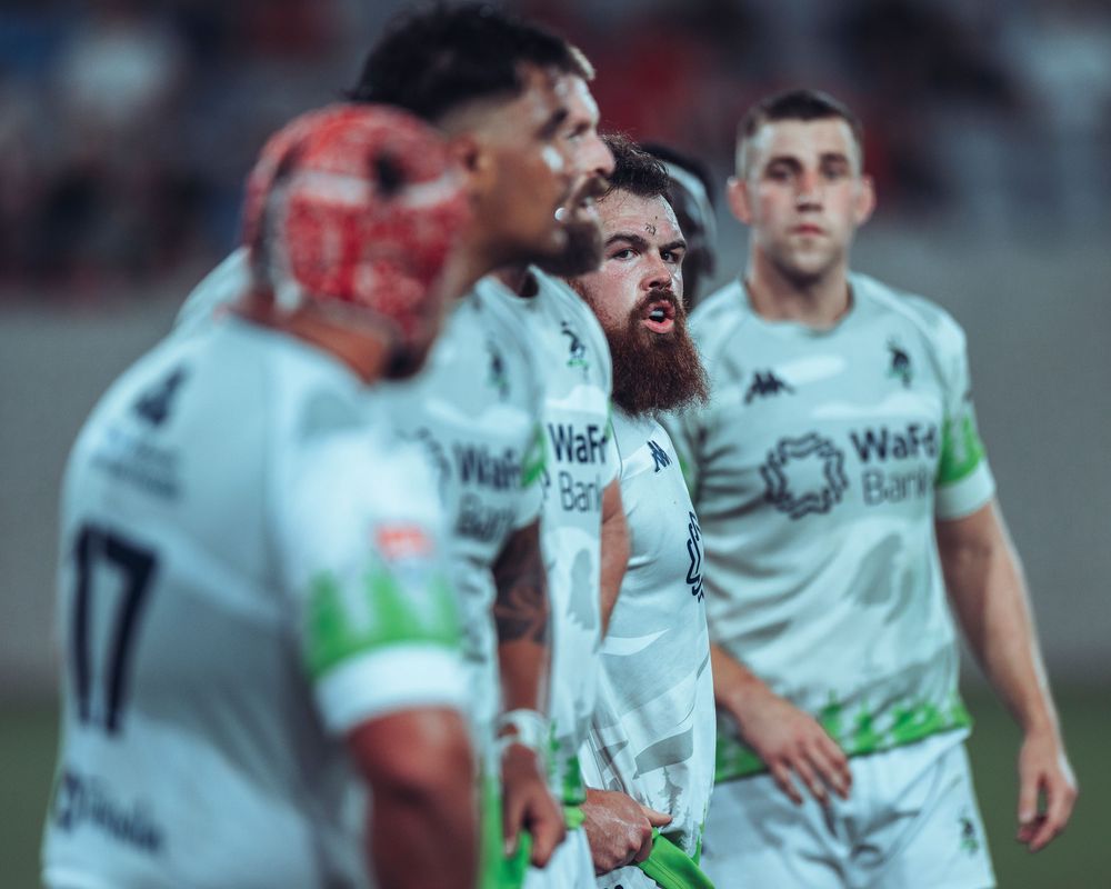 Four players from the Seattle Seawolves Rugby team await instructions from the referee during a match in San Diego. Sports photography