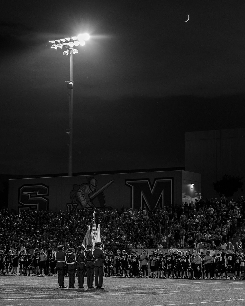 National Anthem ceremony at high school football game showing the colors and the home crowd before kickoff. Sports Photography