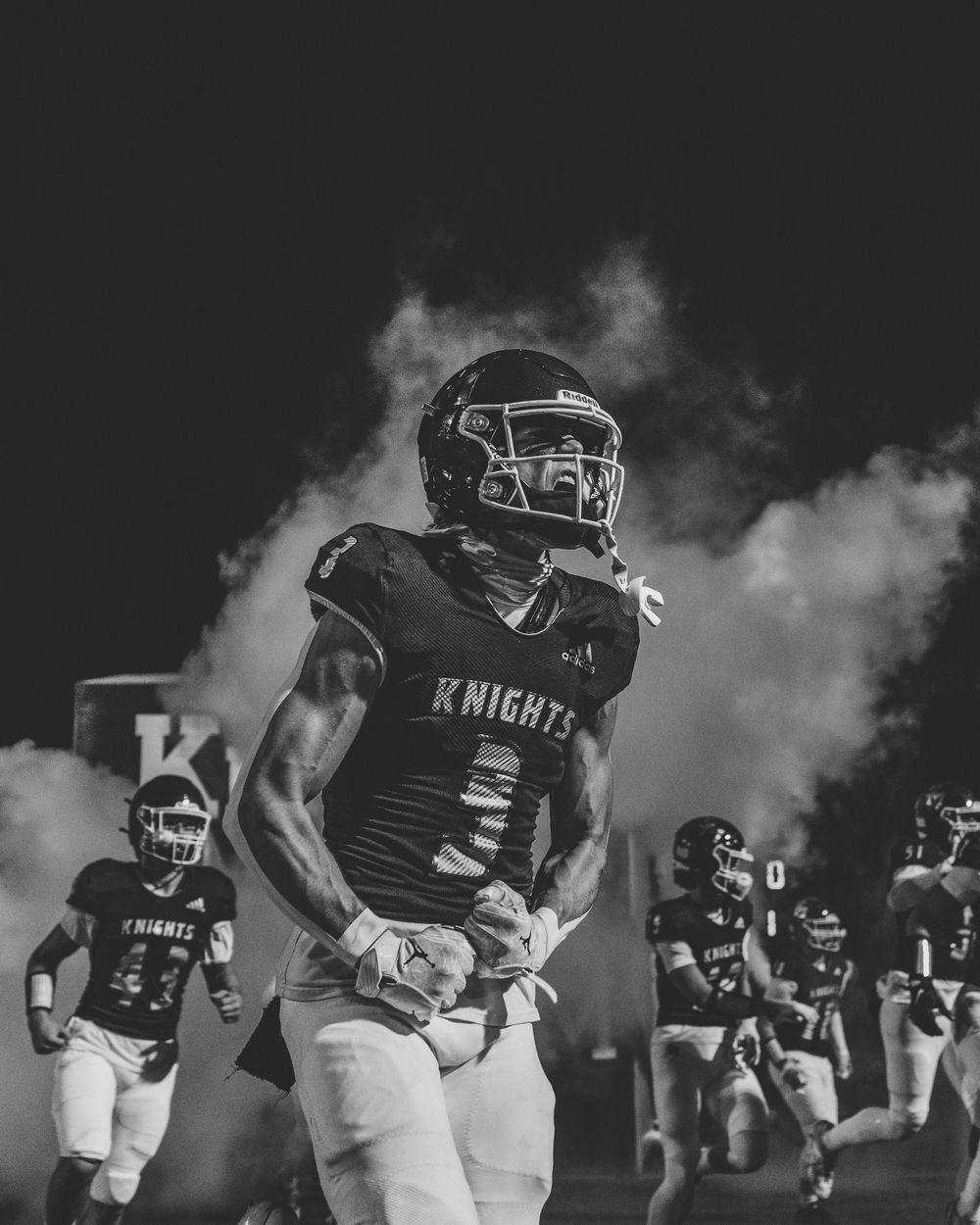 High School football player runs out of the tunnel onto the field during pre-game ceremony, sports photography