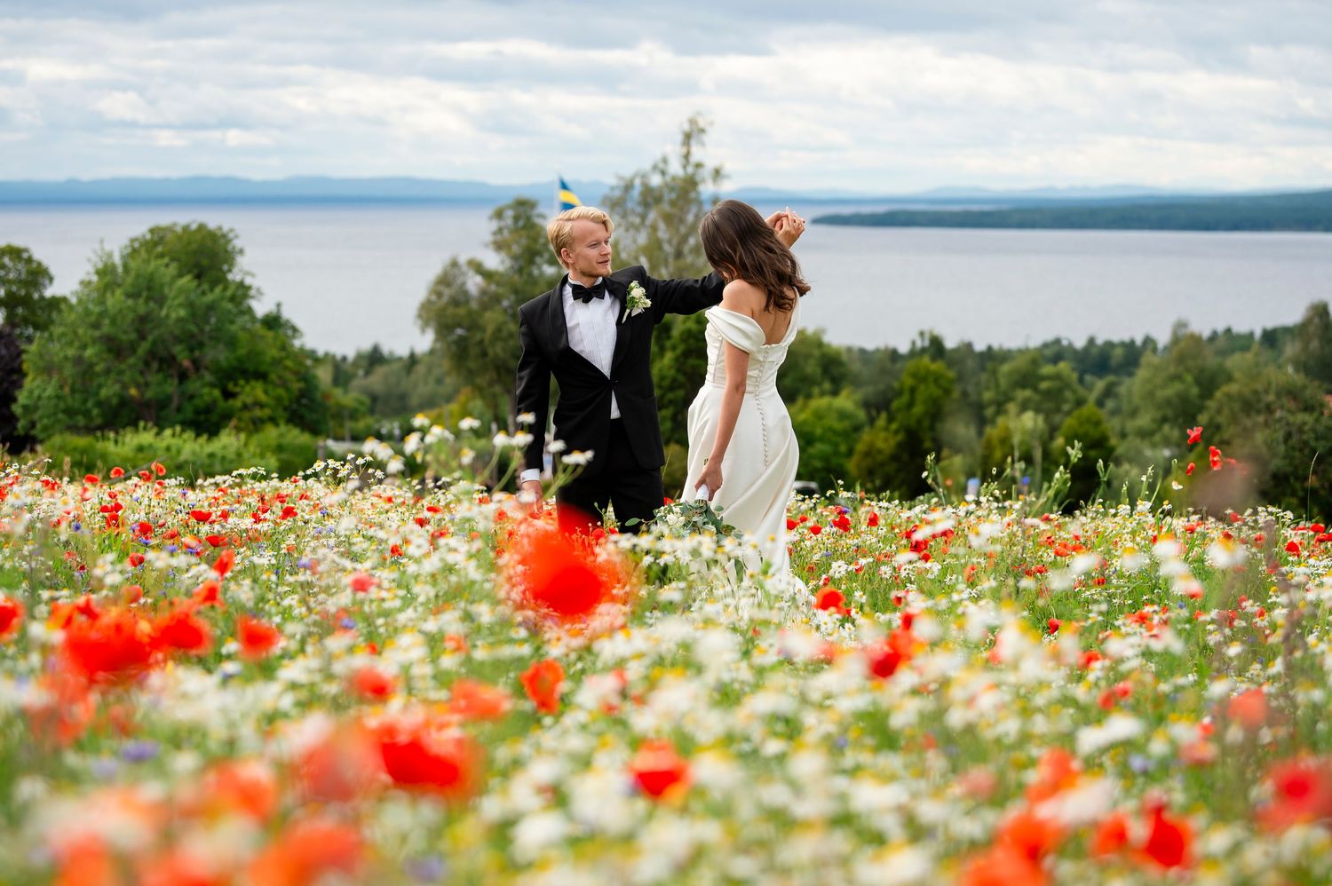 Brudpar i blomsteräng med siljan i bakgrunden