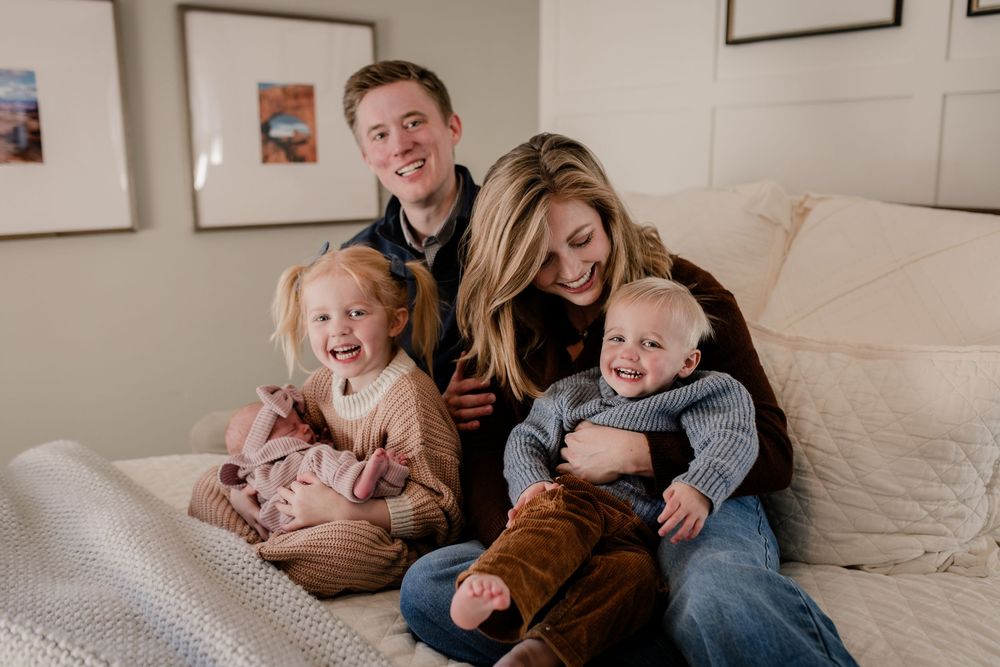 A joyful family shares tender moments together on a light-colored couch in a cozy living room setting.