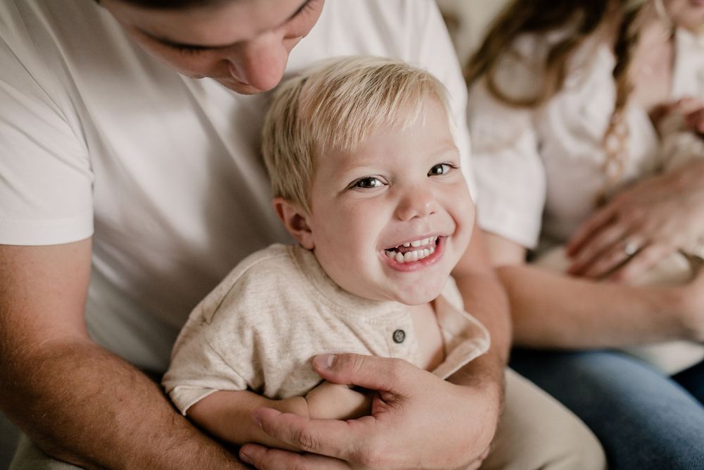 A candid family moment captured on a couch showing playful interaction and joyful expressions.