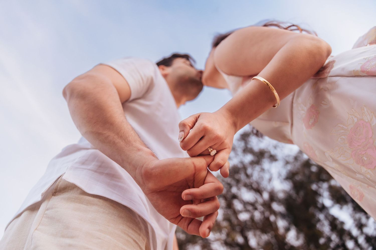 newly engaged couple kissing during engagement photo session at Ellwood Bluffs in Santa Barbara. pinky promise and you can see her ring.