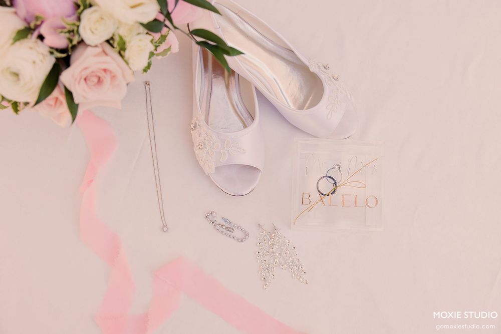 Pink and white wedding decor elements including roses, ribbons, and delicate accessories on a soft pink background.