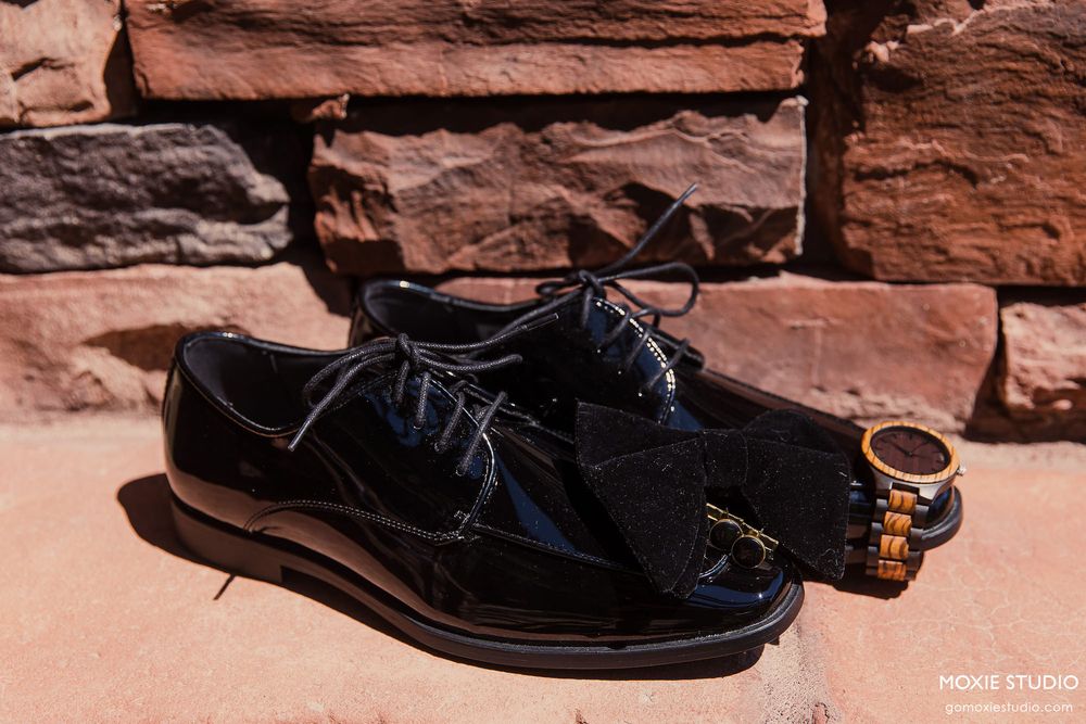 A series of black leather sandals shown against a rustic red rock background in a product photography sequence.