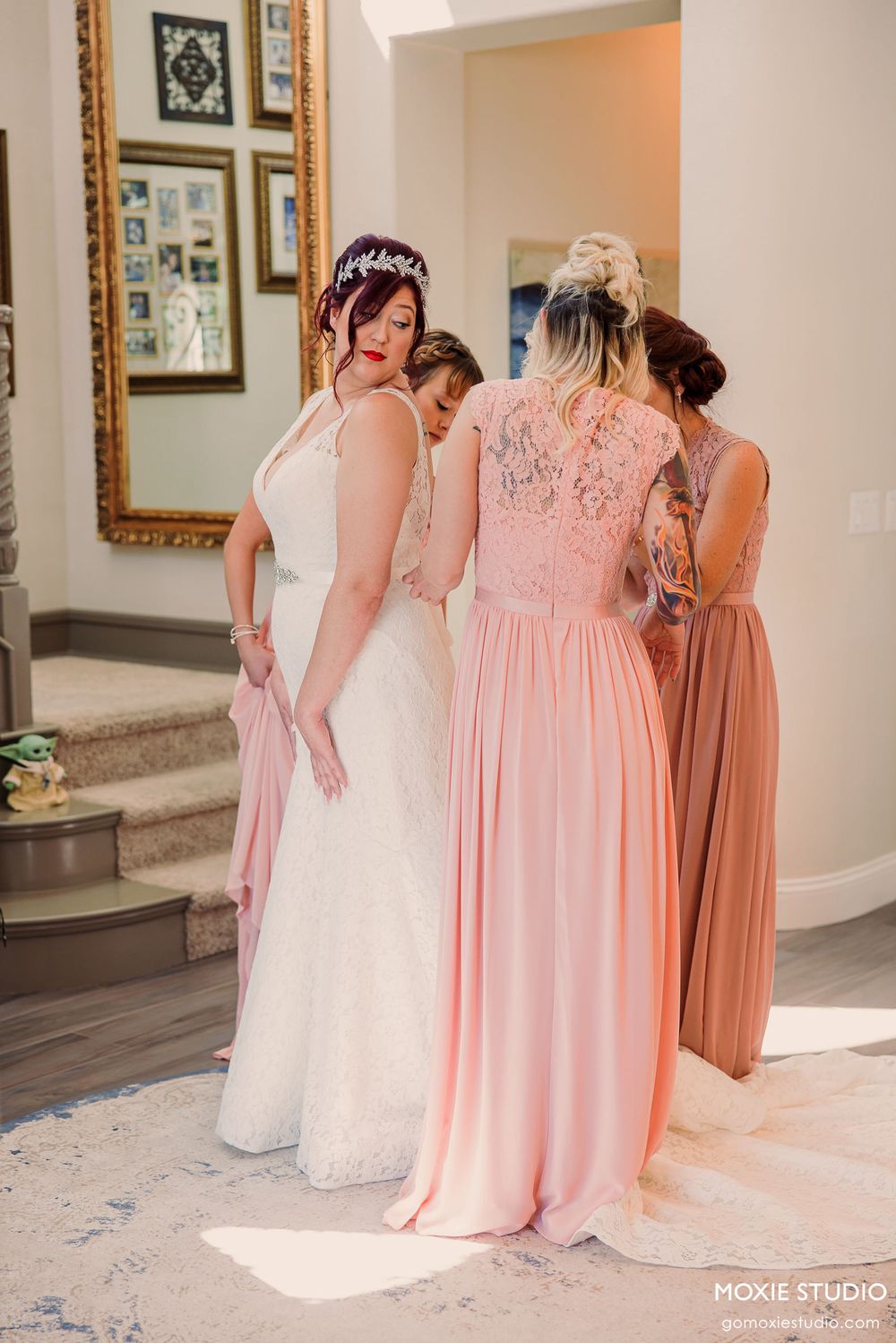 Bridesmaids in flowing pink gowns stand beside a bride in white during a wedding photo session.