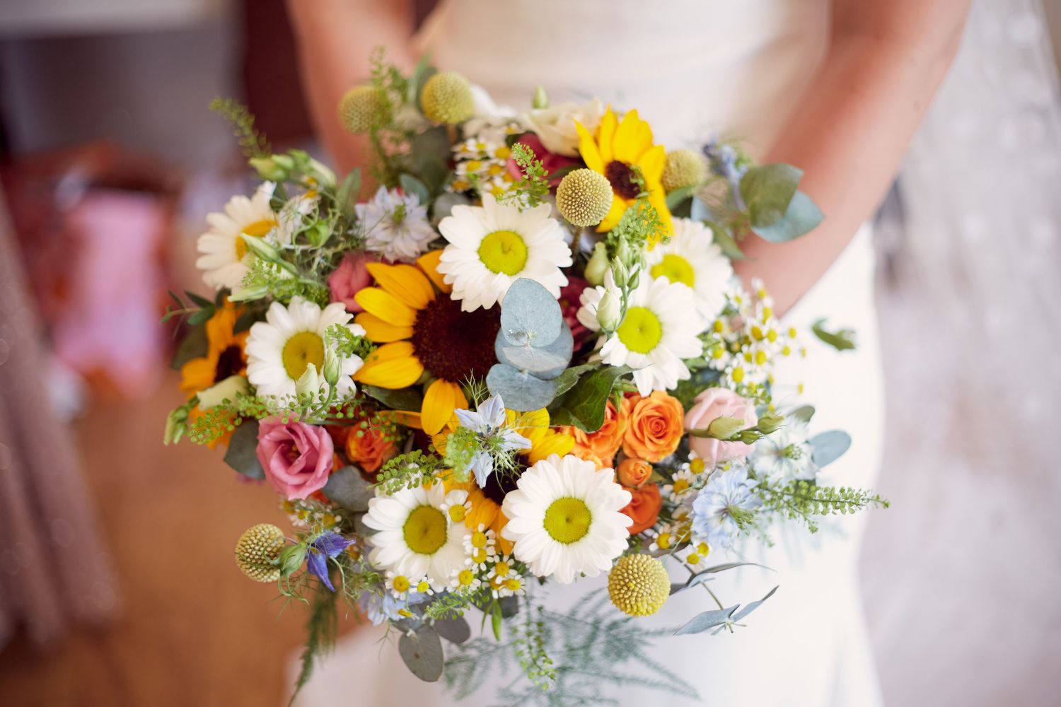 Vibrant bridal bouquet featuring sunflowers, daisies, and colorful mixed flowers.