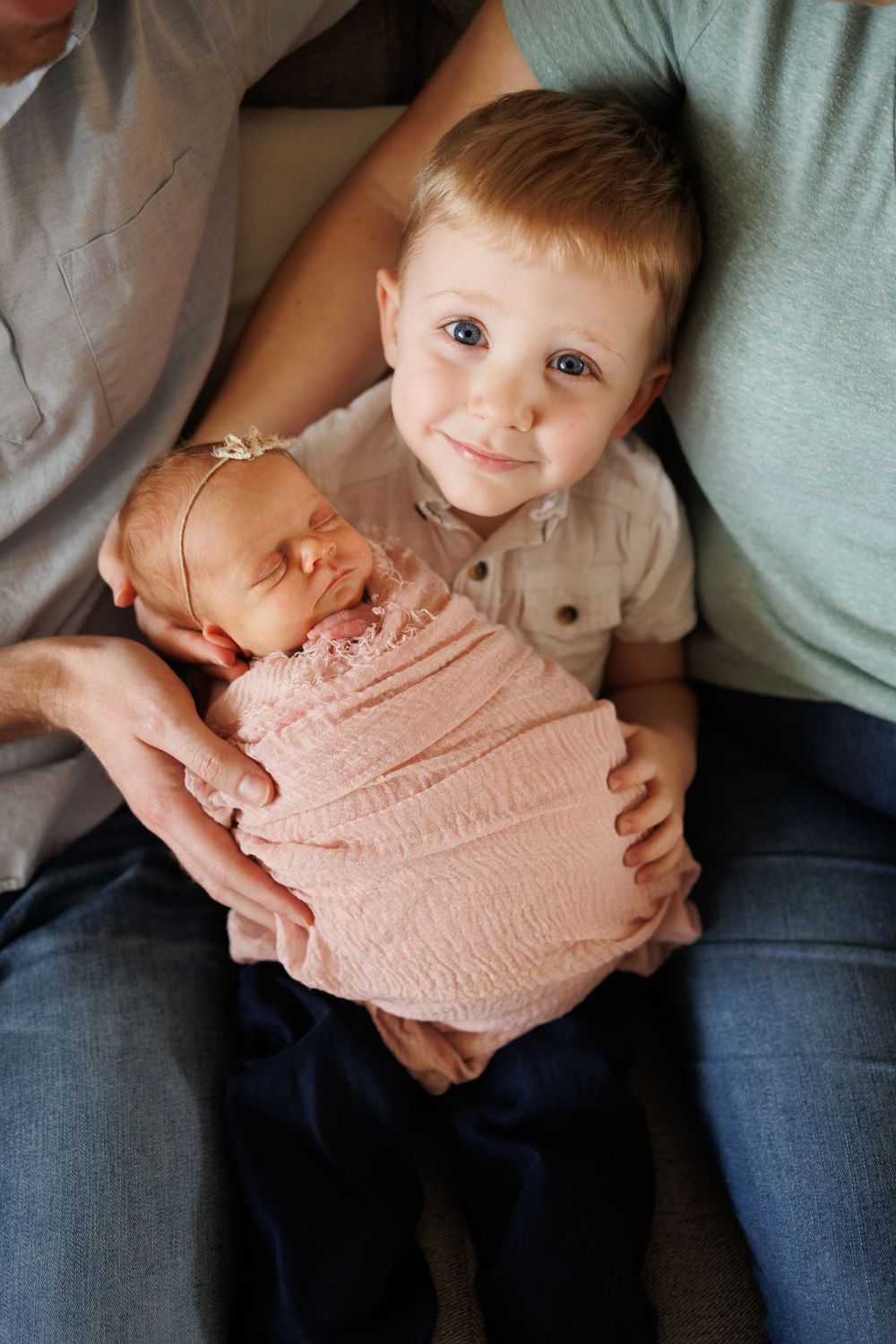 A heartwarming family photo with a young child holding a swaddled newborn.