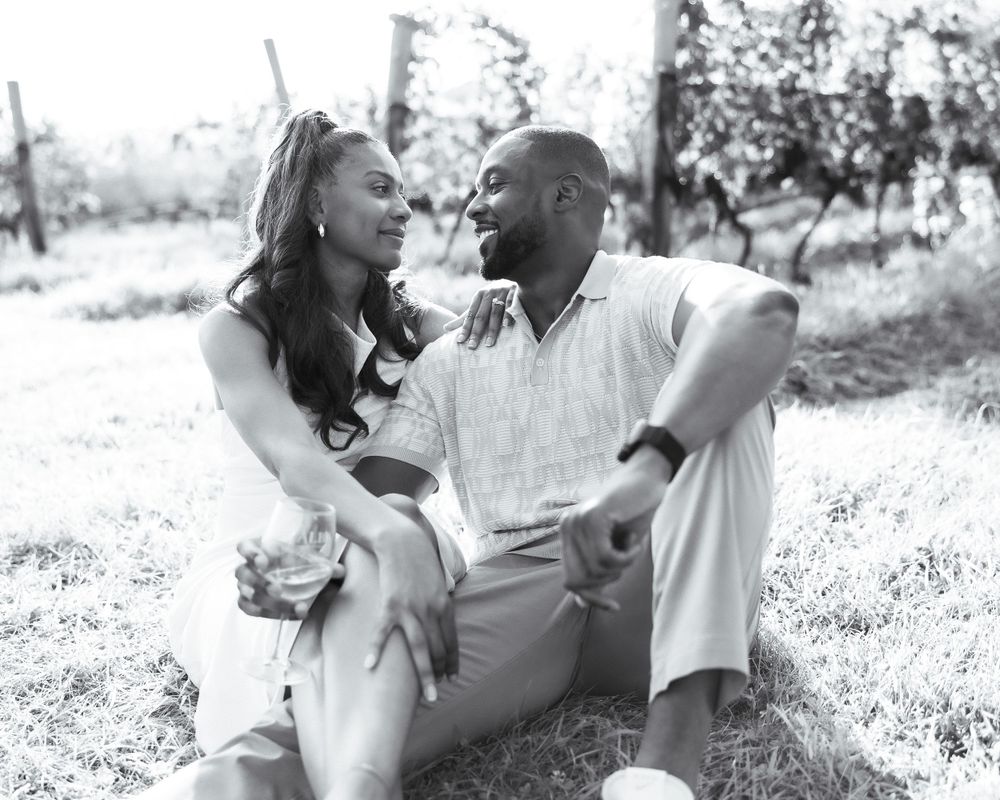A couple shares a joyful moment together outdoors in black and white.