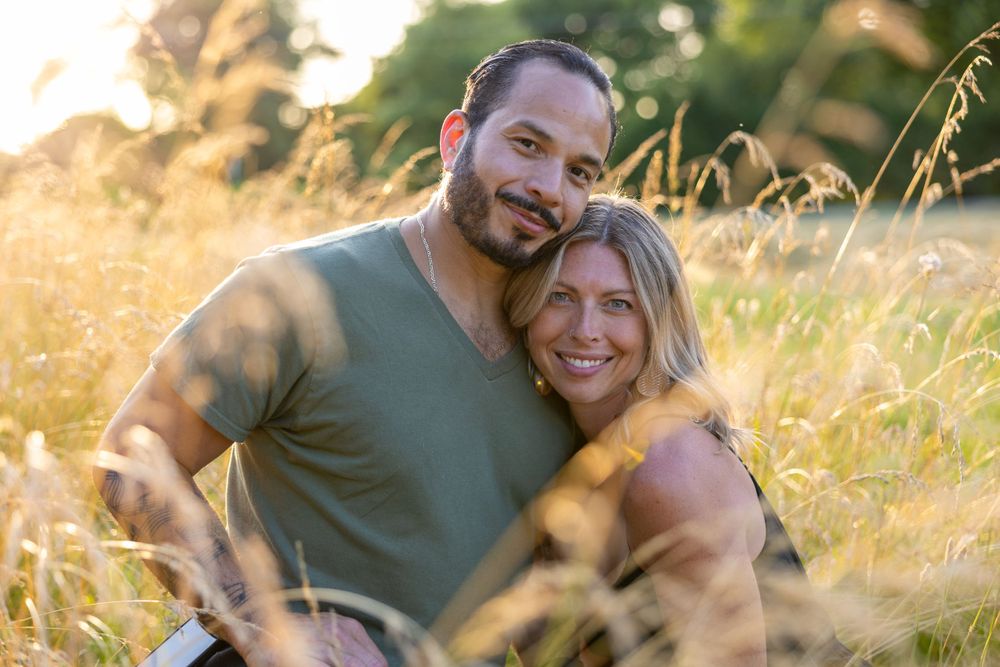 Happy couple embracing in golden sunlit meadow during summer.