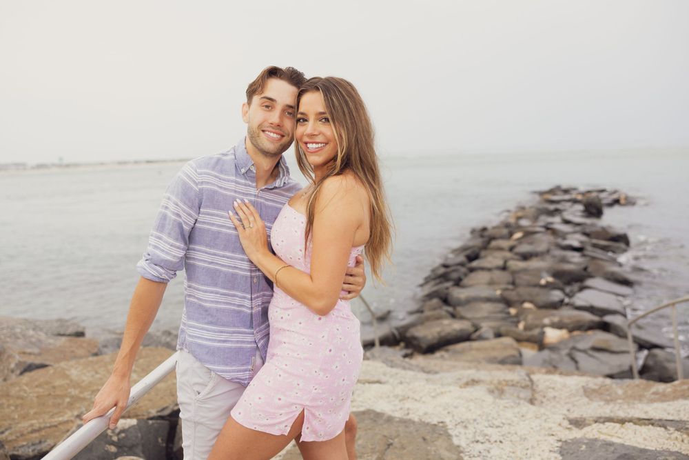 A joyful couple laughs together on a rocky beach.