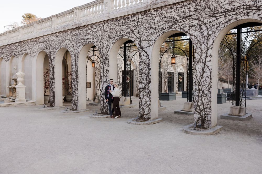 Elegant stone archways decorated with intricate white branch designs create a covered walkway in an urban setting.