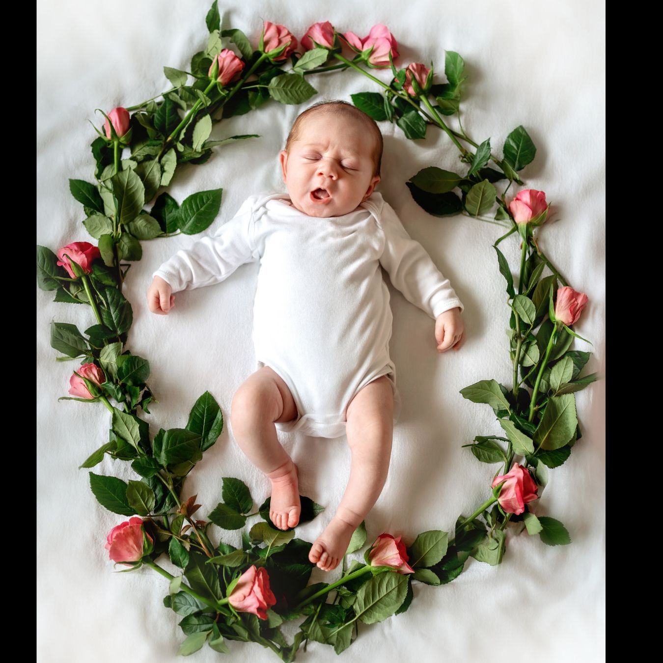 The newborn baby is yawning in a flower wreath. Location: Barton on Sea, Hampshire.