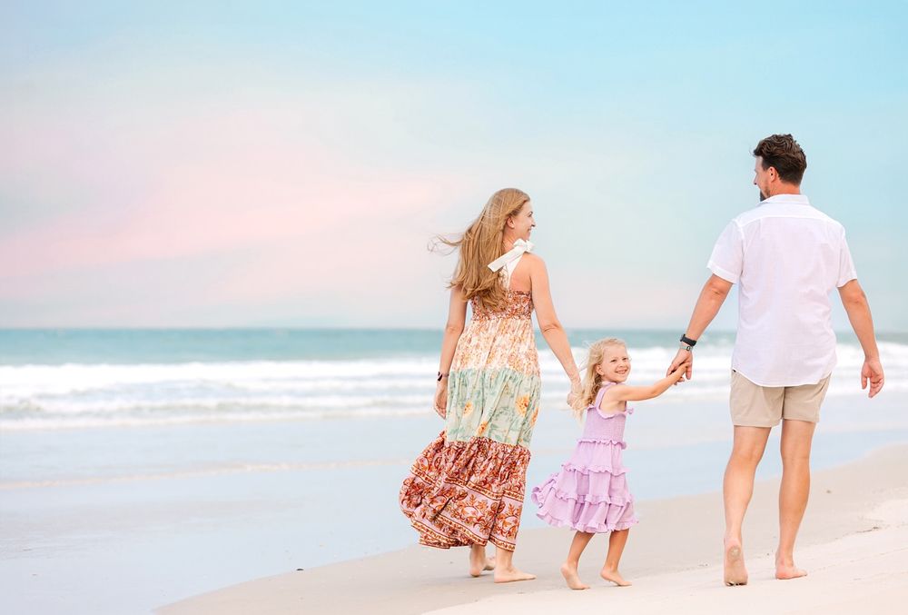 Family walking together along a peaceful beach at sunset, holding hands and enjoying the ocean view.