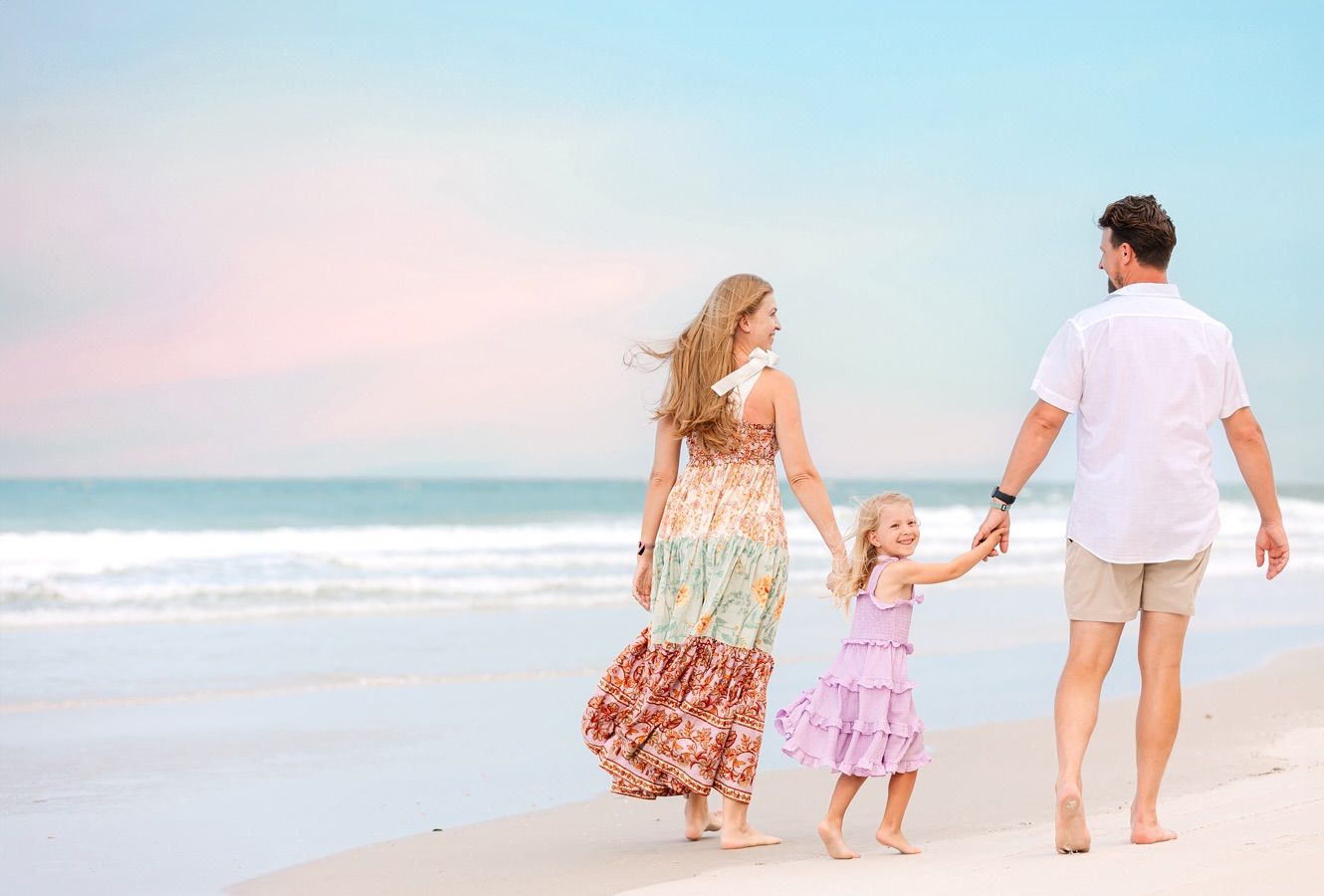 Family walking together along a peaceful beach at sunset, holding hands and enjoying the ocean view.