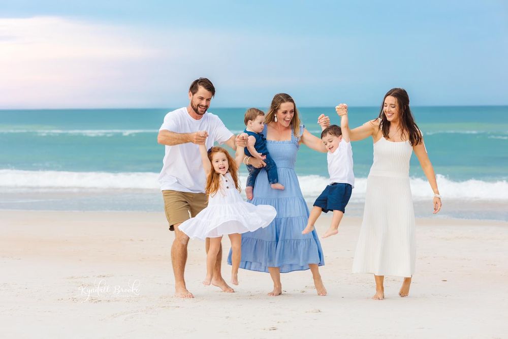 A group of people walking together on a white sandy beach wearing coordinated blue and white outfits.