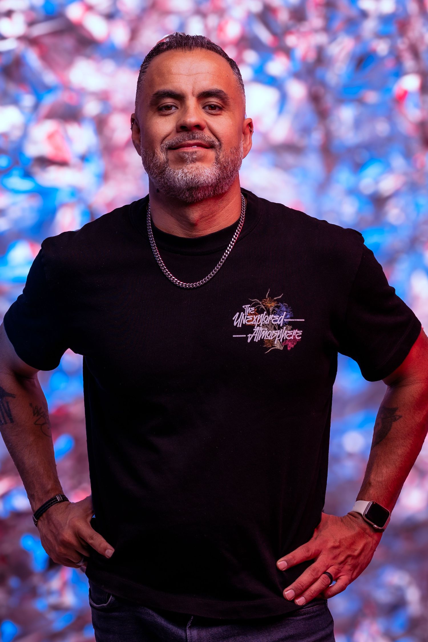 Person in black t-shirt posing against colorful bokeh background.