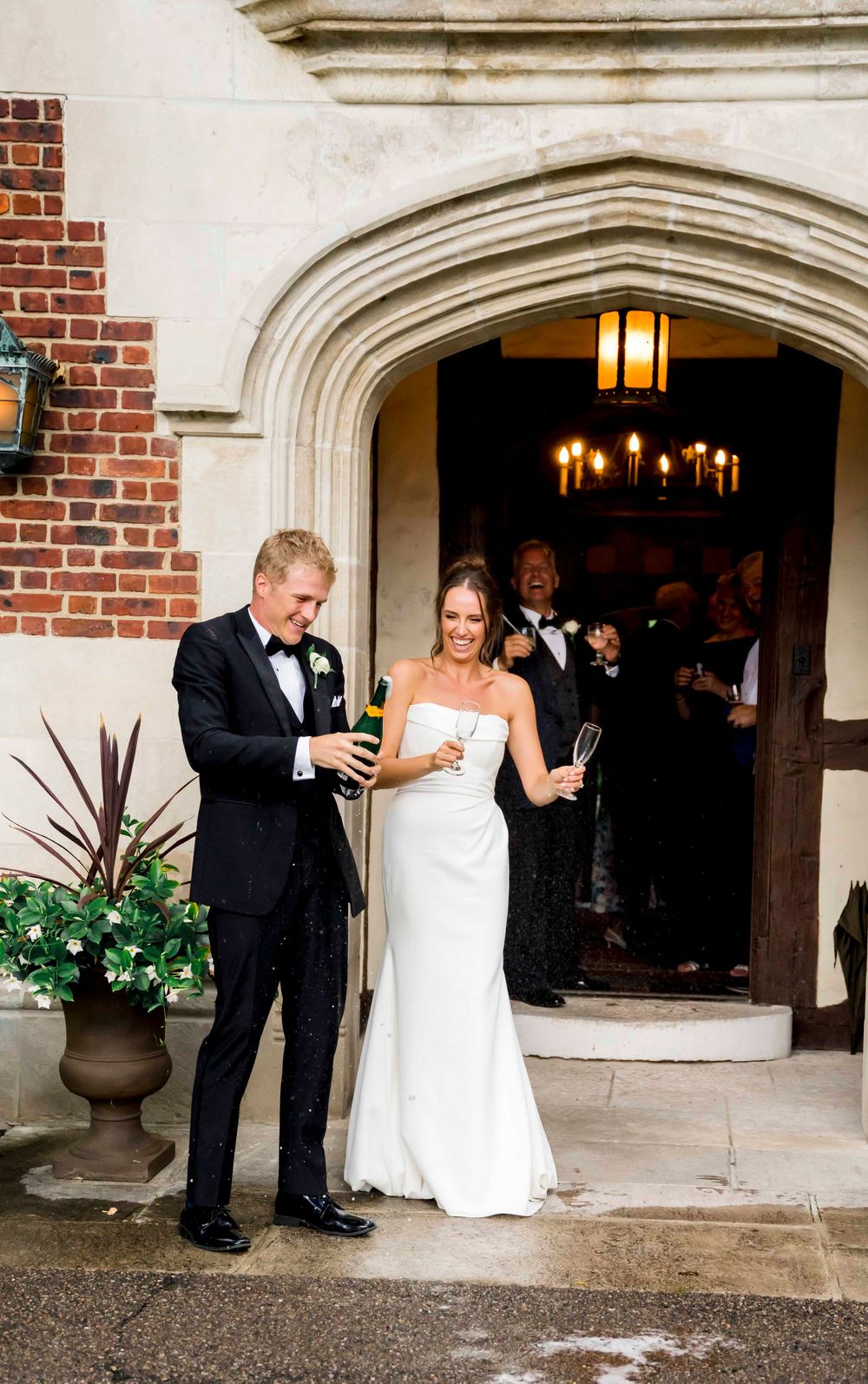 A bride and groom sharing a lighthearted moment under brick archways during their wedding day celebrations.