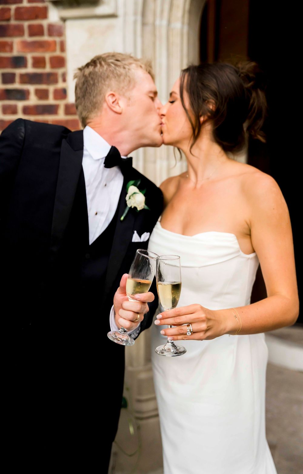 A romantic wedding portrait series shows a couple in formal attire sharing champagne and tender kisses against a brick wall.