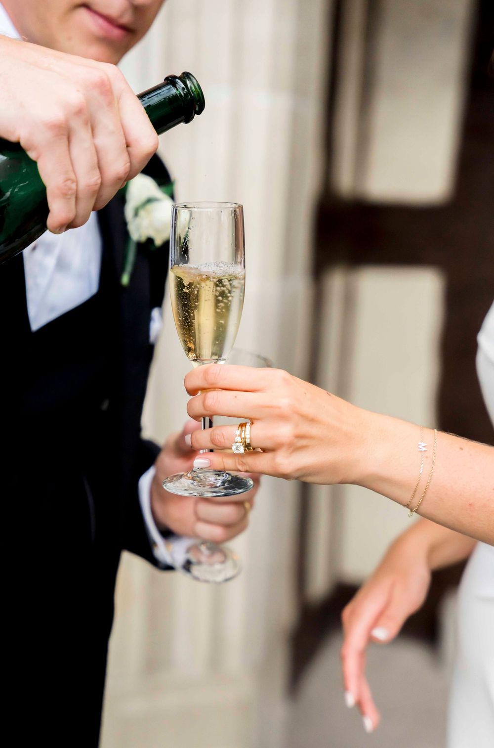 Champagne being poured into an elegant flute glass at a formal event, with hands visible wearing formal attire.