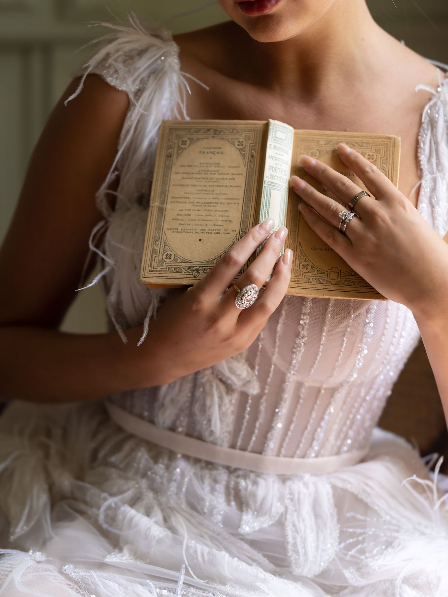 Close-up of hands holding vintage book while wearing romantic lace wedding dress.