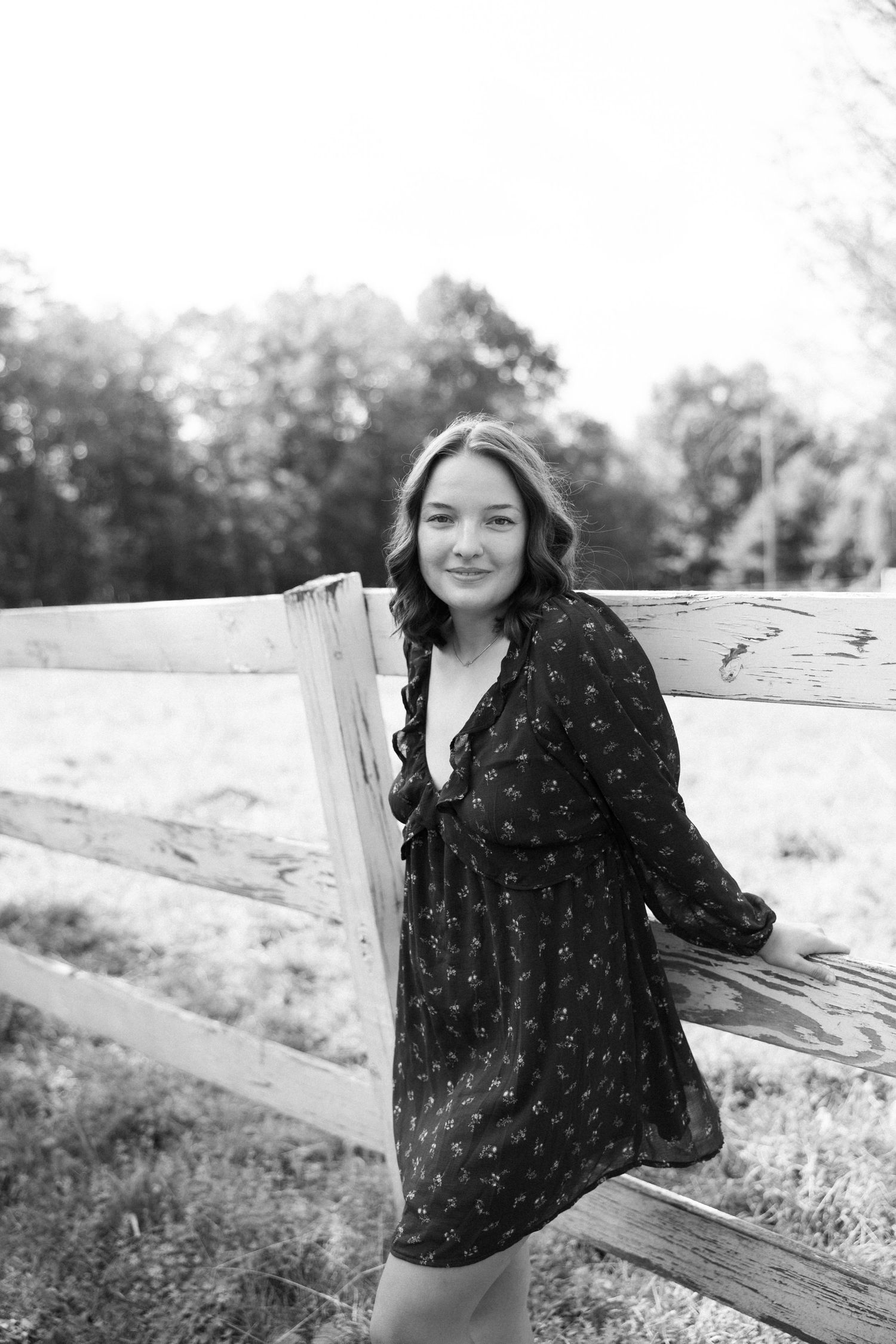 A woman in a white dress stands in a black and white orchard with blossoming trees.