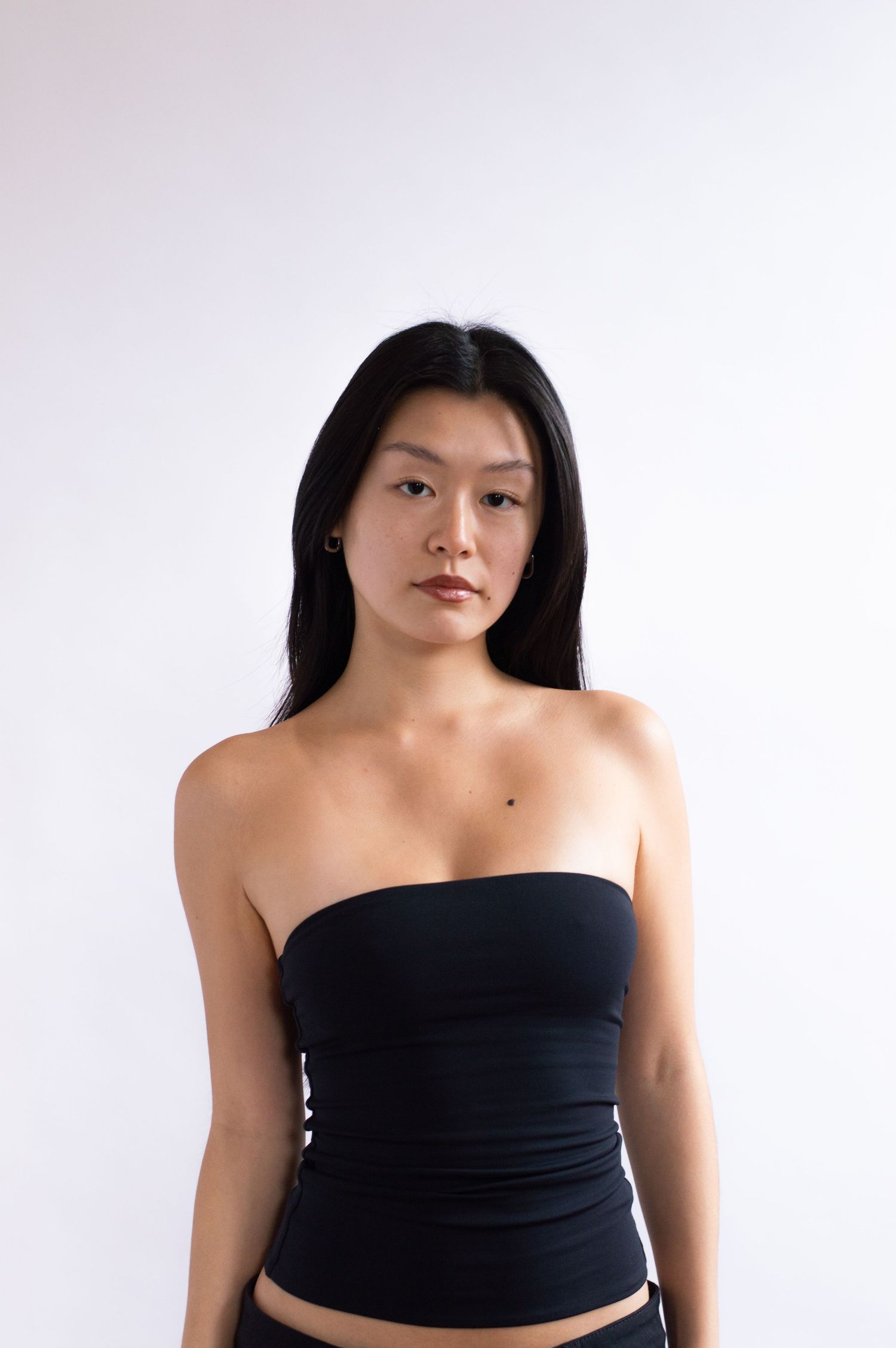 Casual portrait in white ribbed tank top and jeans against white background.