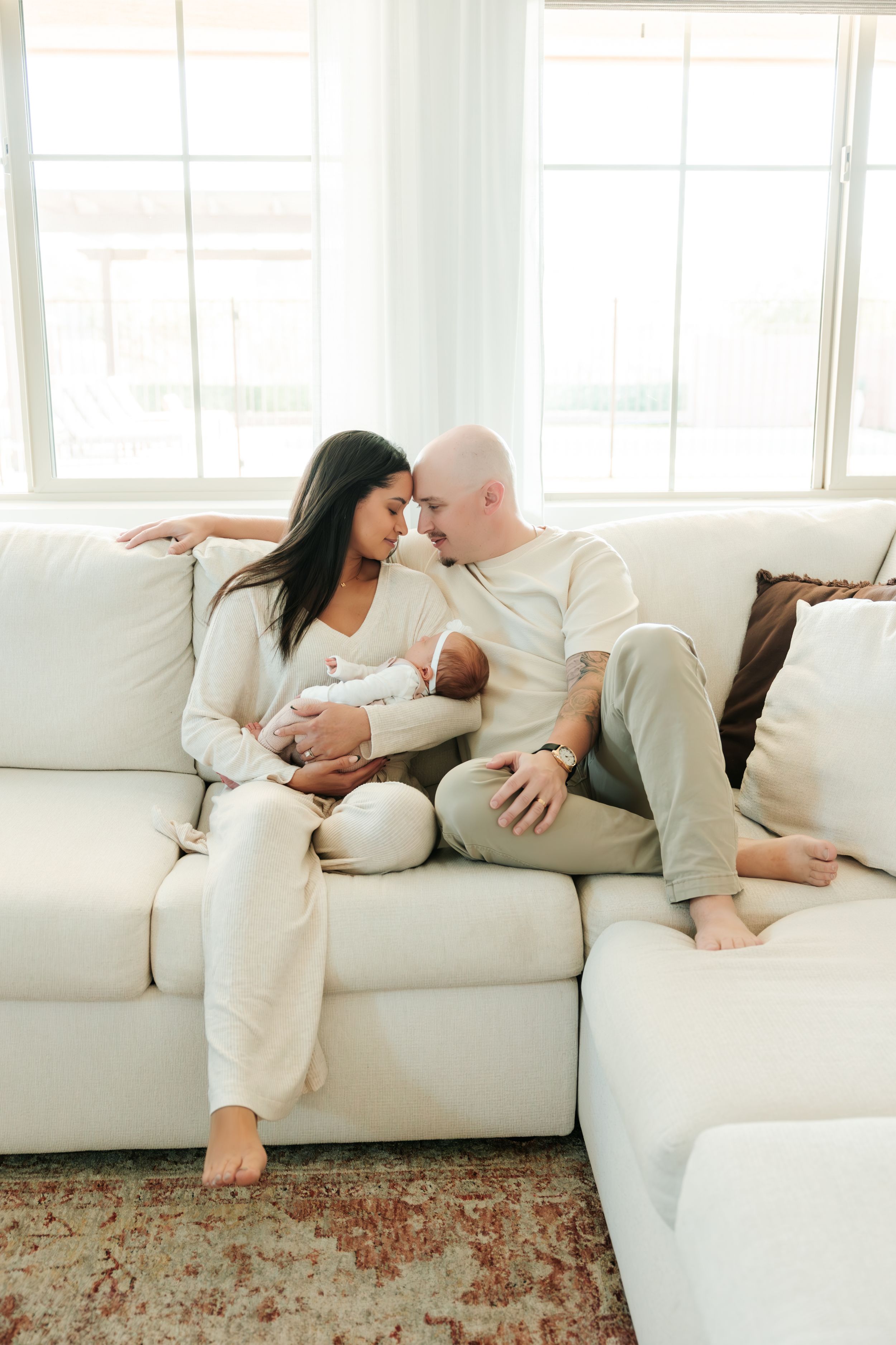 Intimate couple lounging together on white couch in modern bright room with patterned rug.