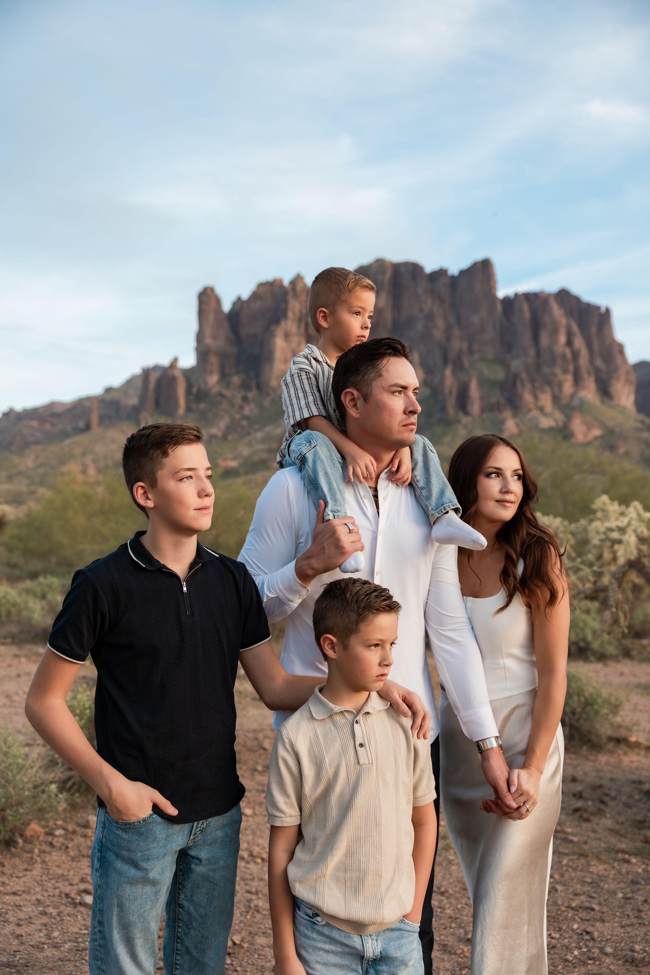 A family poses together against a backdrop of rugged desert mountains and rock formations in the American Southwest.