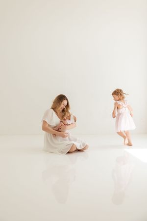 Simple timeless portraits of mother and child in soft white studio wearing delicate dresses against minimalist backdrop.