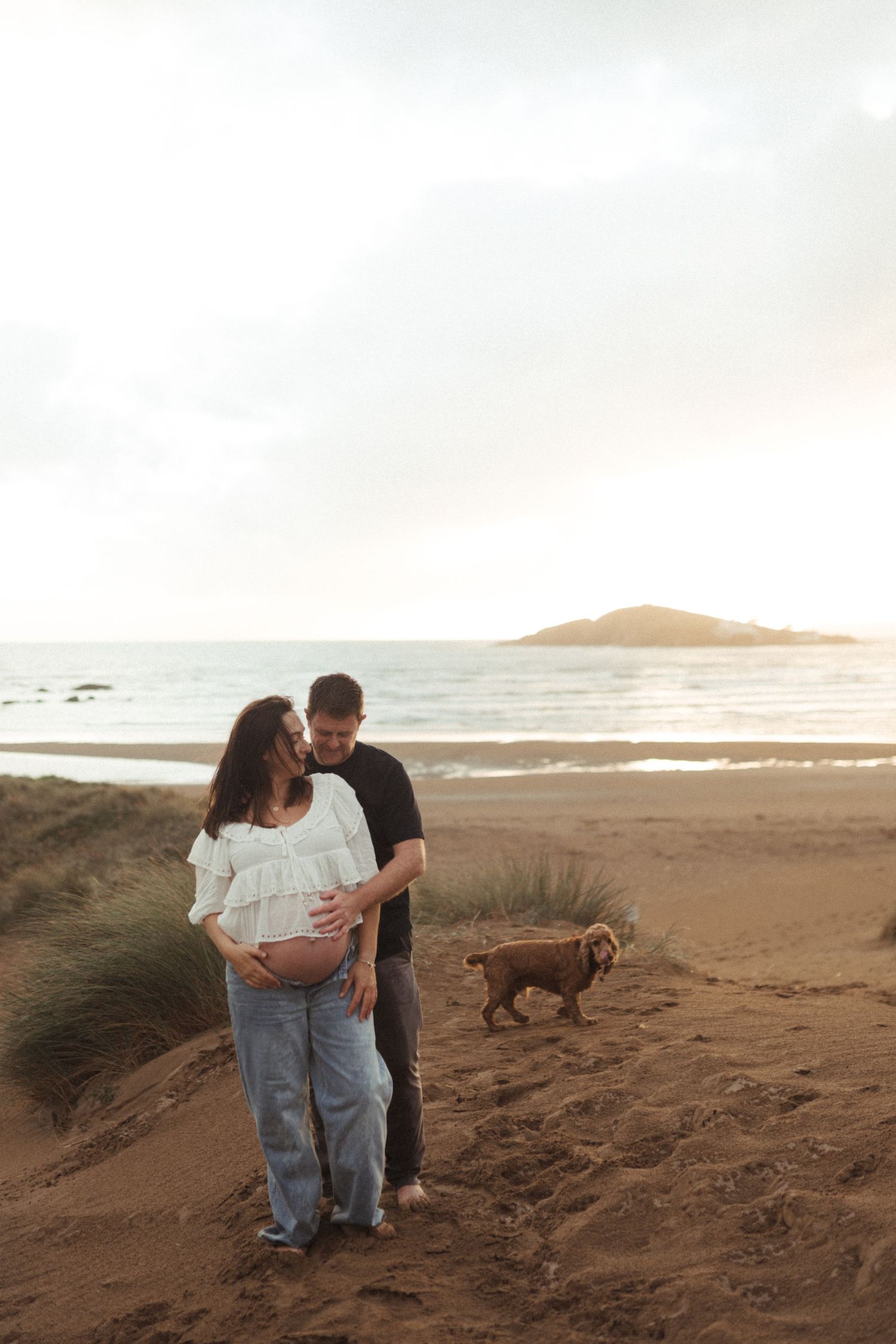 Family enjoying a peaceful moment together on a scenic coastal beach. Natural family & newborn photographer, Devon & South Hams