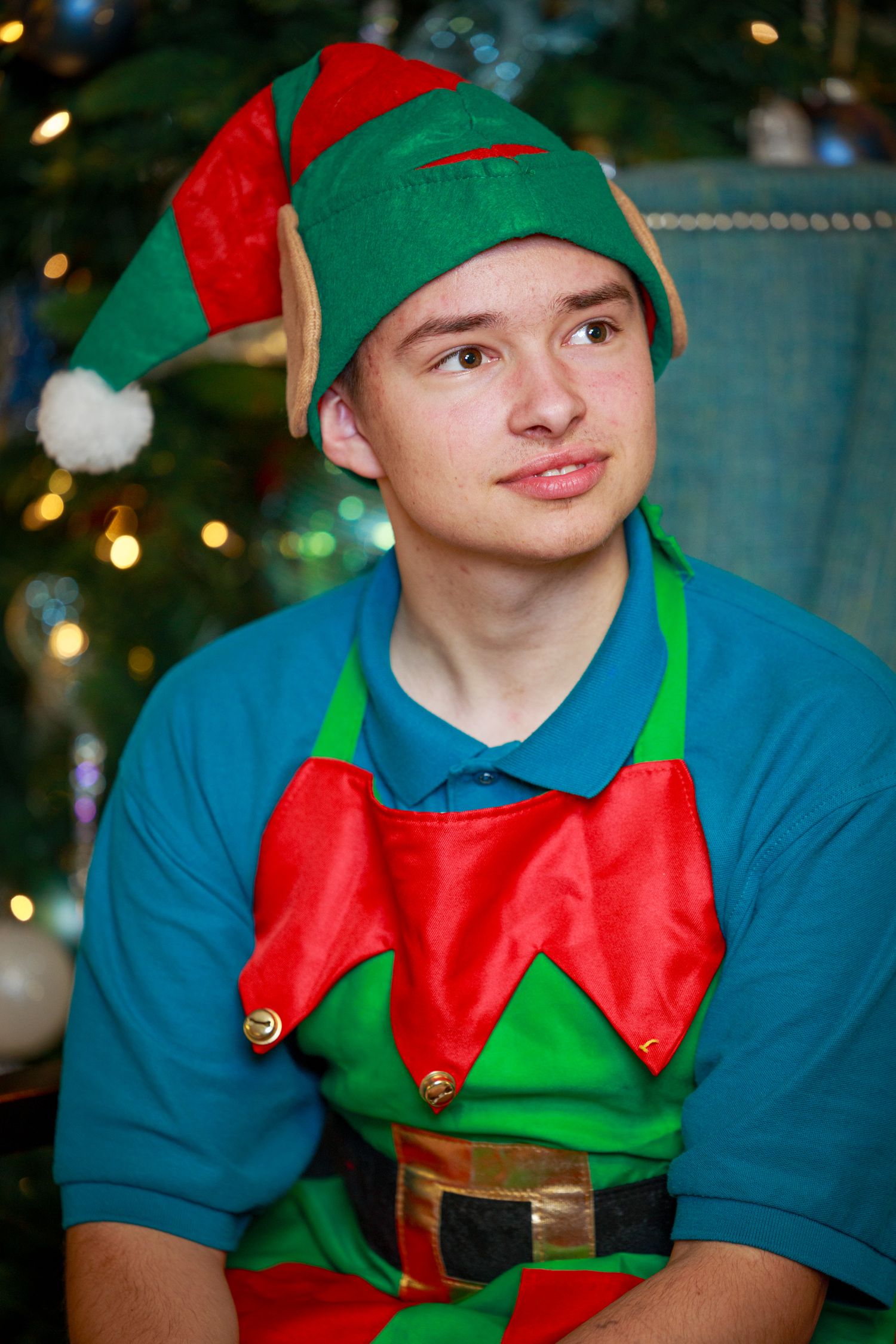Festive holiday elf in blue shirt and green hat with red accents shown in sequence of four similar poses.