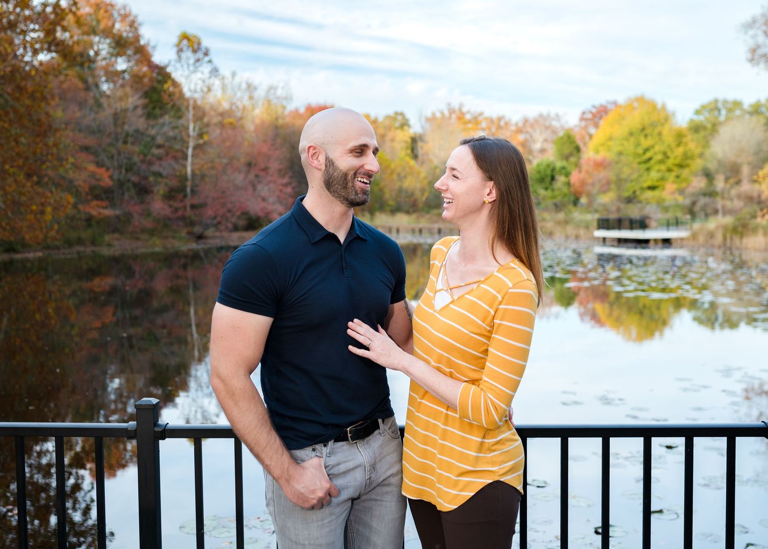 Couple in black and yellow outfits sharing romantic moments by a scenic lake during autumn.