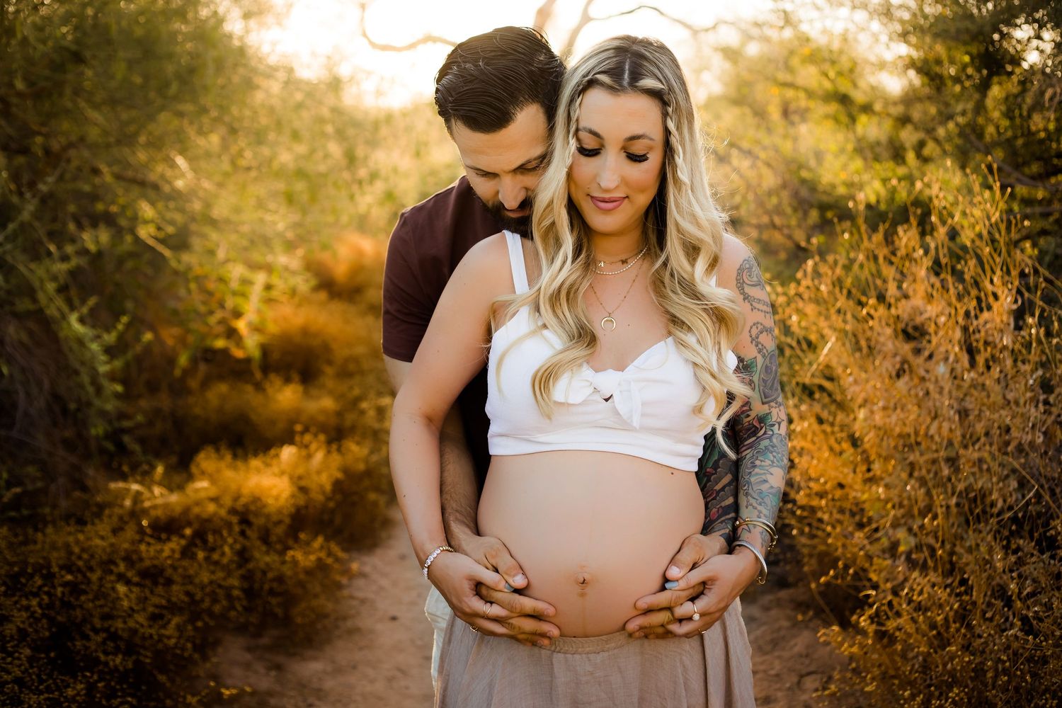 A loving maternity portrait of a couple snuggling the moms baby belly together in a desert location during fall in Arizona.