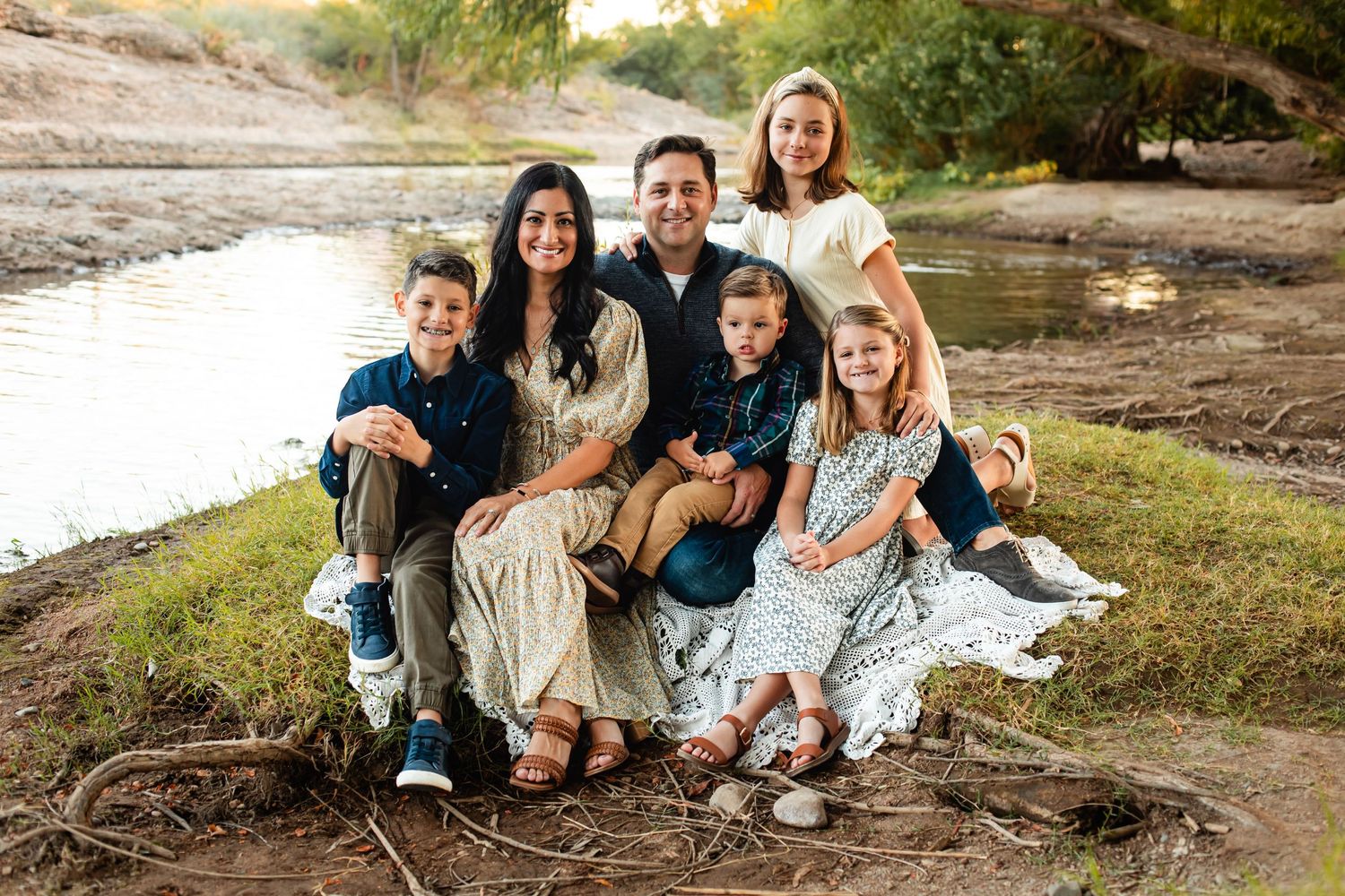 Family photo of six sitting near the bank of a beautiful river in Arizona on a sunny day.