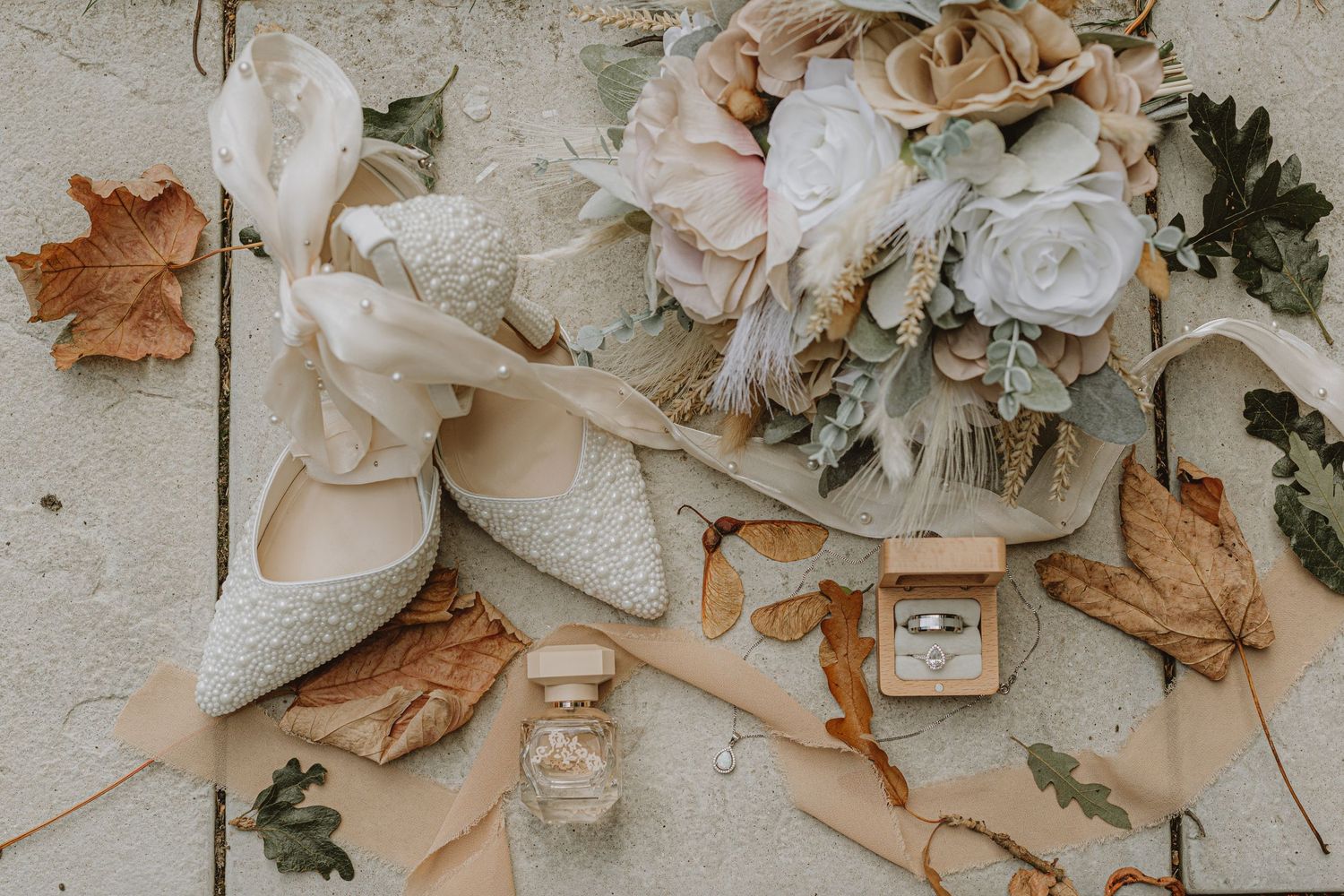 Delicate flat lay of dried flowers and wedding details in neutral tones.