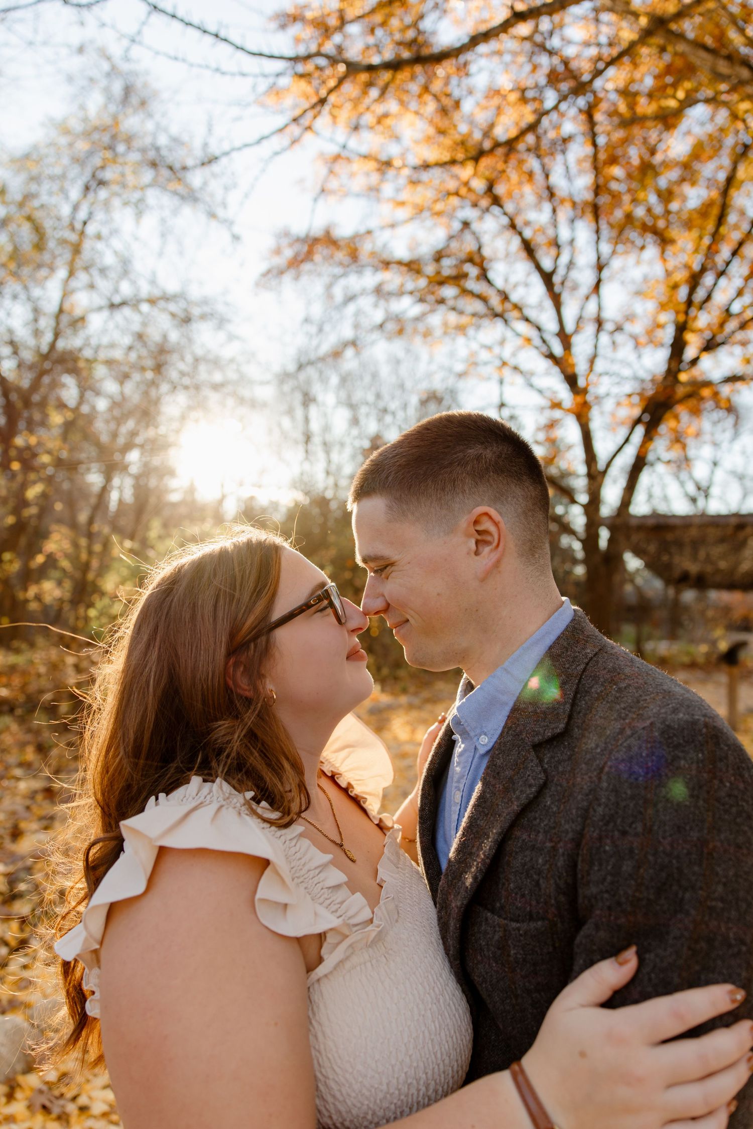 Romantic autumn portrait with sunlight streaming through golden leaves.
