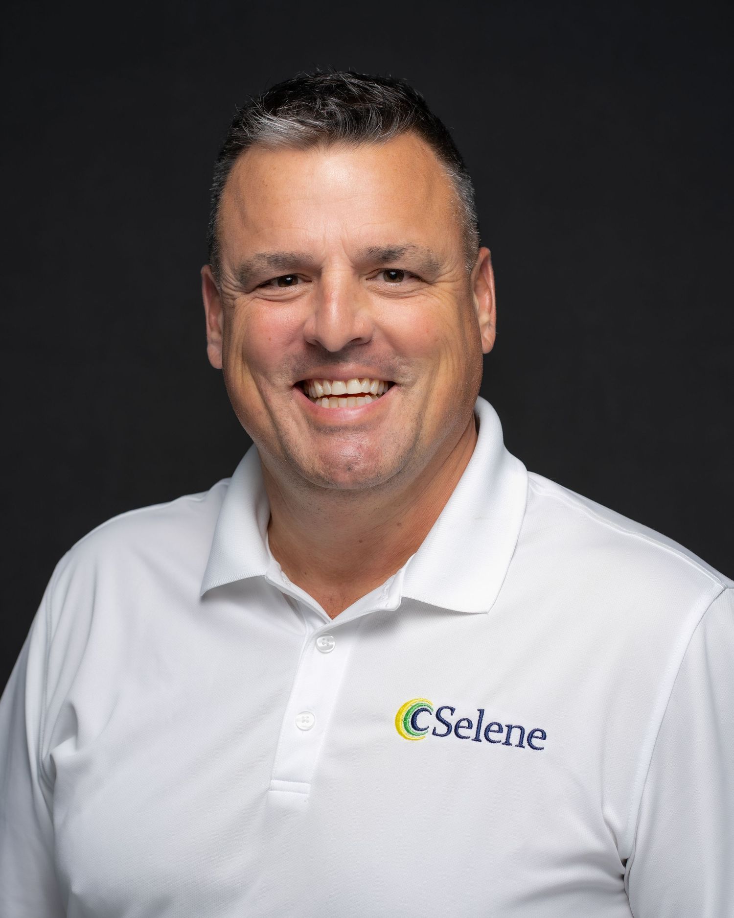 Smiling man in white a polo shirt posing for a professional headshot
