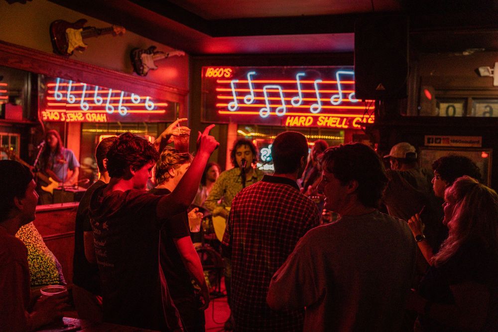 Bar scene illuminated by vibrant red neon signs creating atmospheric ambiance.