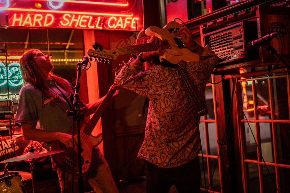 Musicians perform under red neon lighting at Hard Shell Cafe.