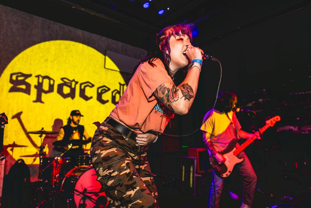 Rock concert performance with colorful stage lighting and yellow backdrop.