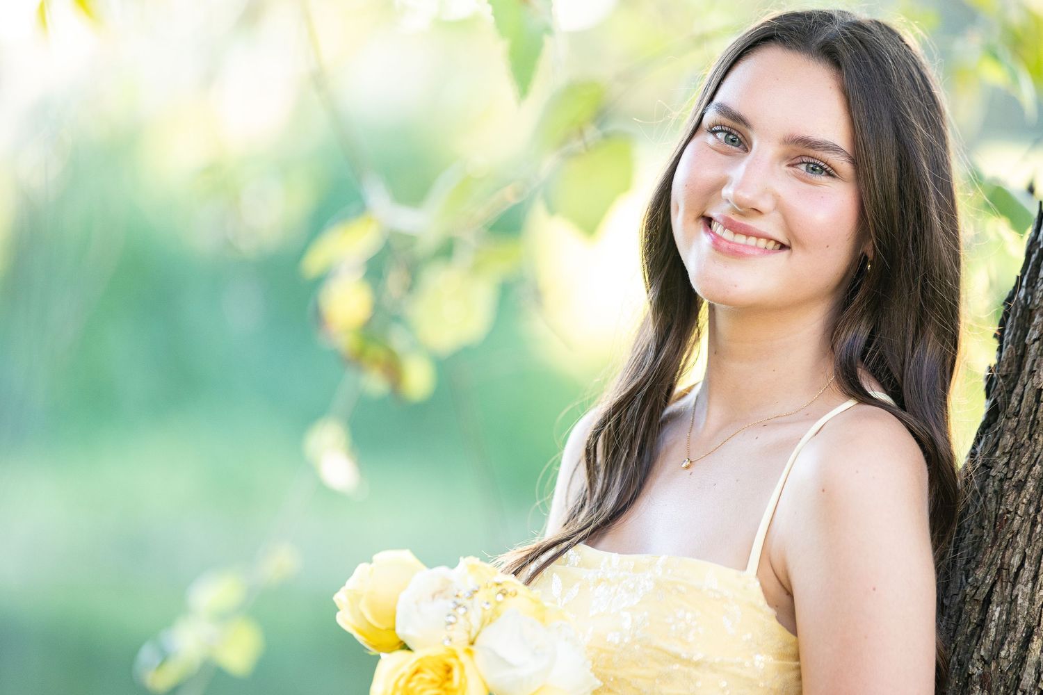A person in a white dress poses in a sunny garden setting with yellow flowers and natural lighting.