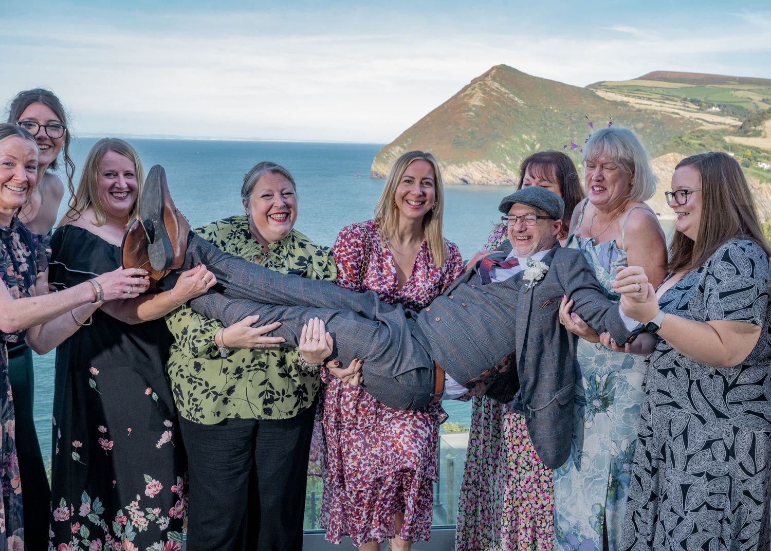 A celebratory group photo taken against a coastal backdrop with dramatic cliffs.