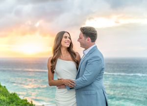 A couple in wedding attire shares intimate moments during a beachside photoshoot at sunset.
