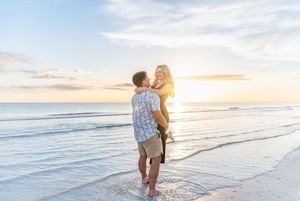 A couple shares a romantic moment on the beach during sunset as gentle waves roll onto the shore.