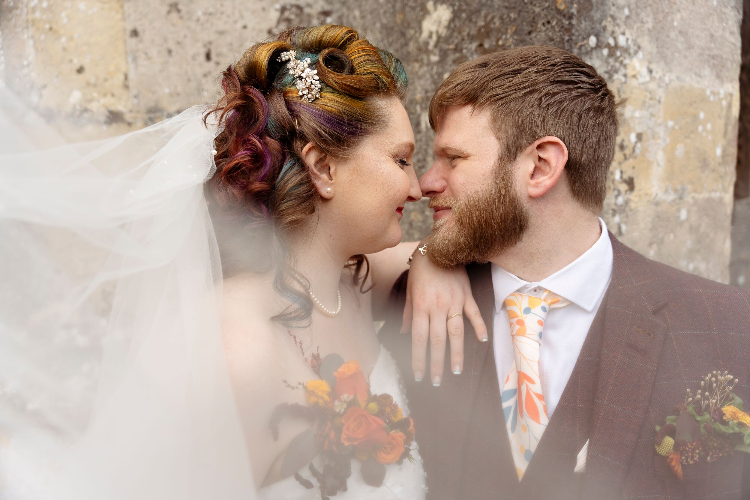 Intimate wedding portrait with couple sharing tender moment through bridal veil.