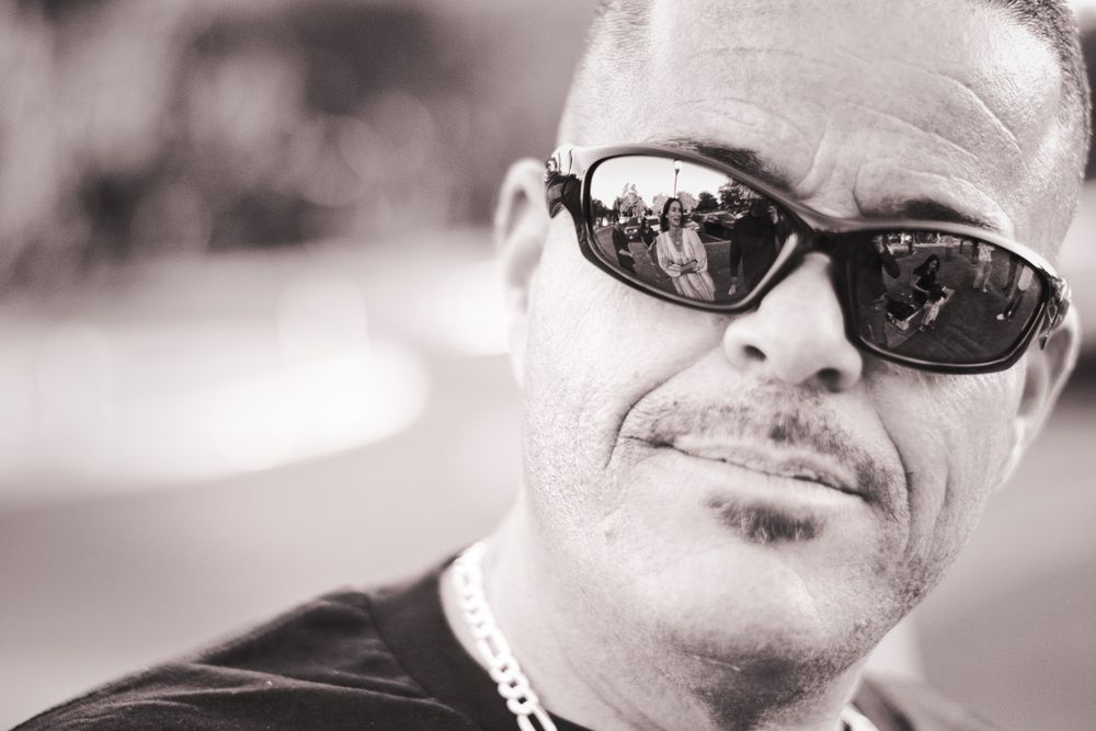 Black and white portrait of someone wearing sunglasses with a slight smile.