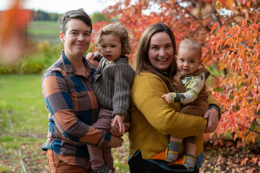 Outside portrait of family holding two young children in fall colors.