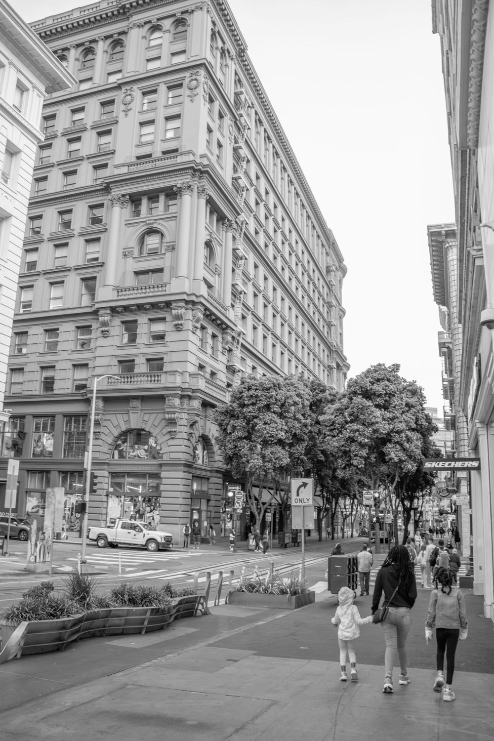 Historic San Francisco building facade with ornate architecture and pedestrians walking on a city street.
